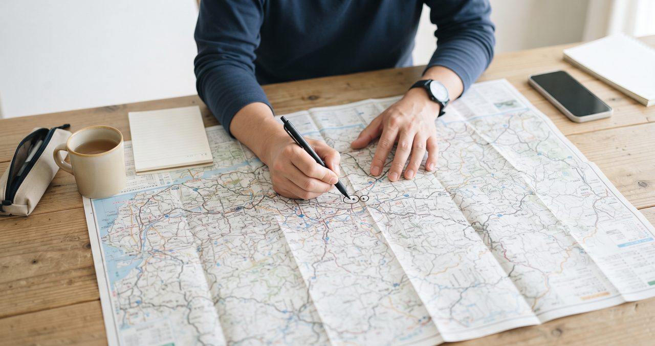地図を広げて2つの離れた地点を確認しながら異動先を考えている手元の様子